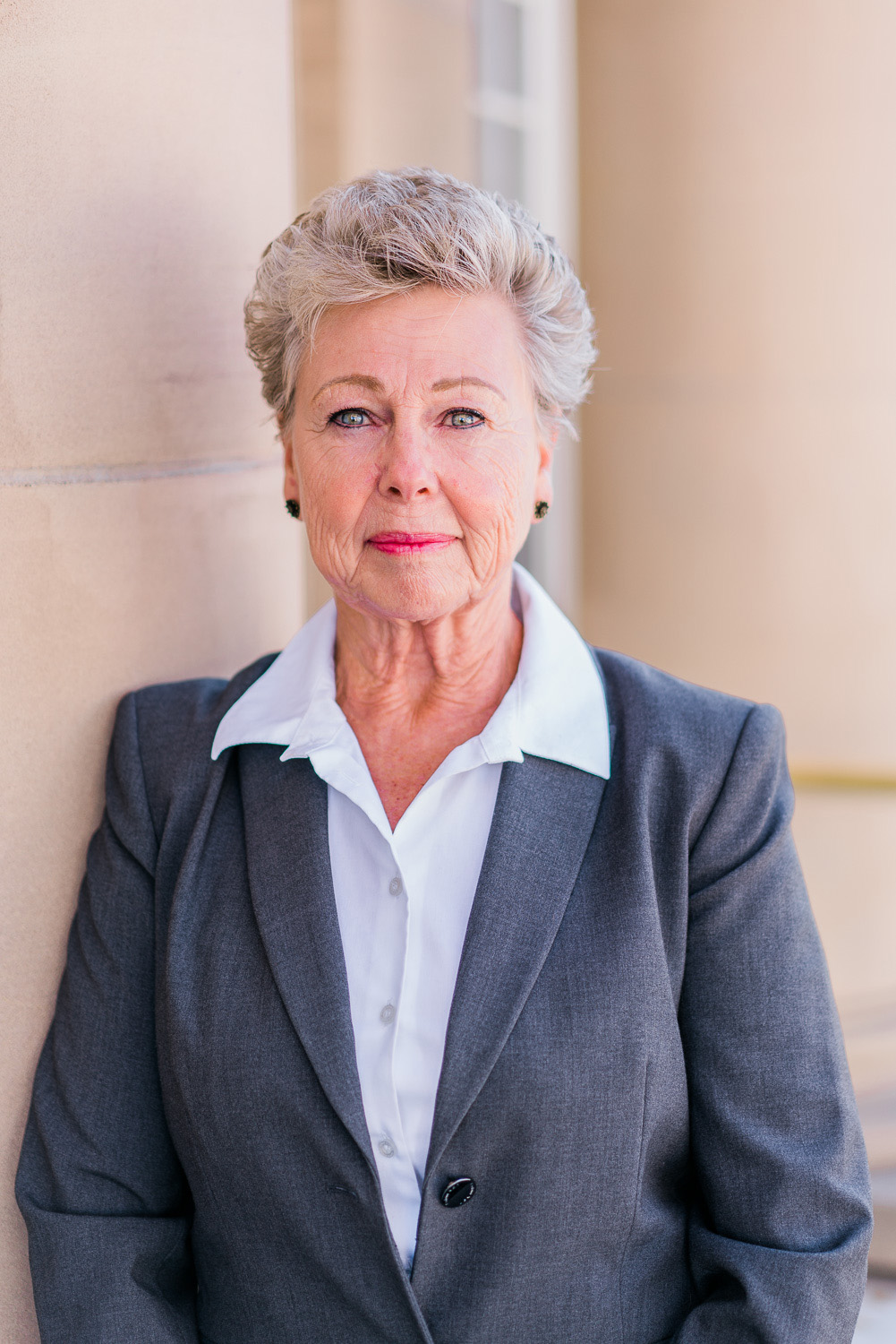 Kathy Carlson, CFDE, CQDE, certified and court-qualified forensic document examiner, standing against a courthouse wall in a professional suit.